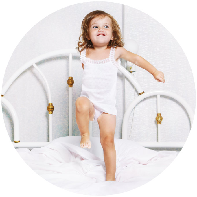Active toddler girl dancing in bed